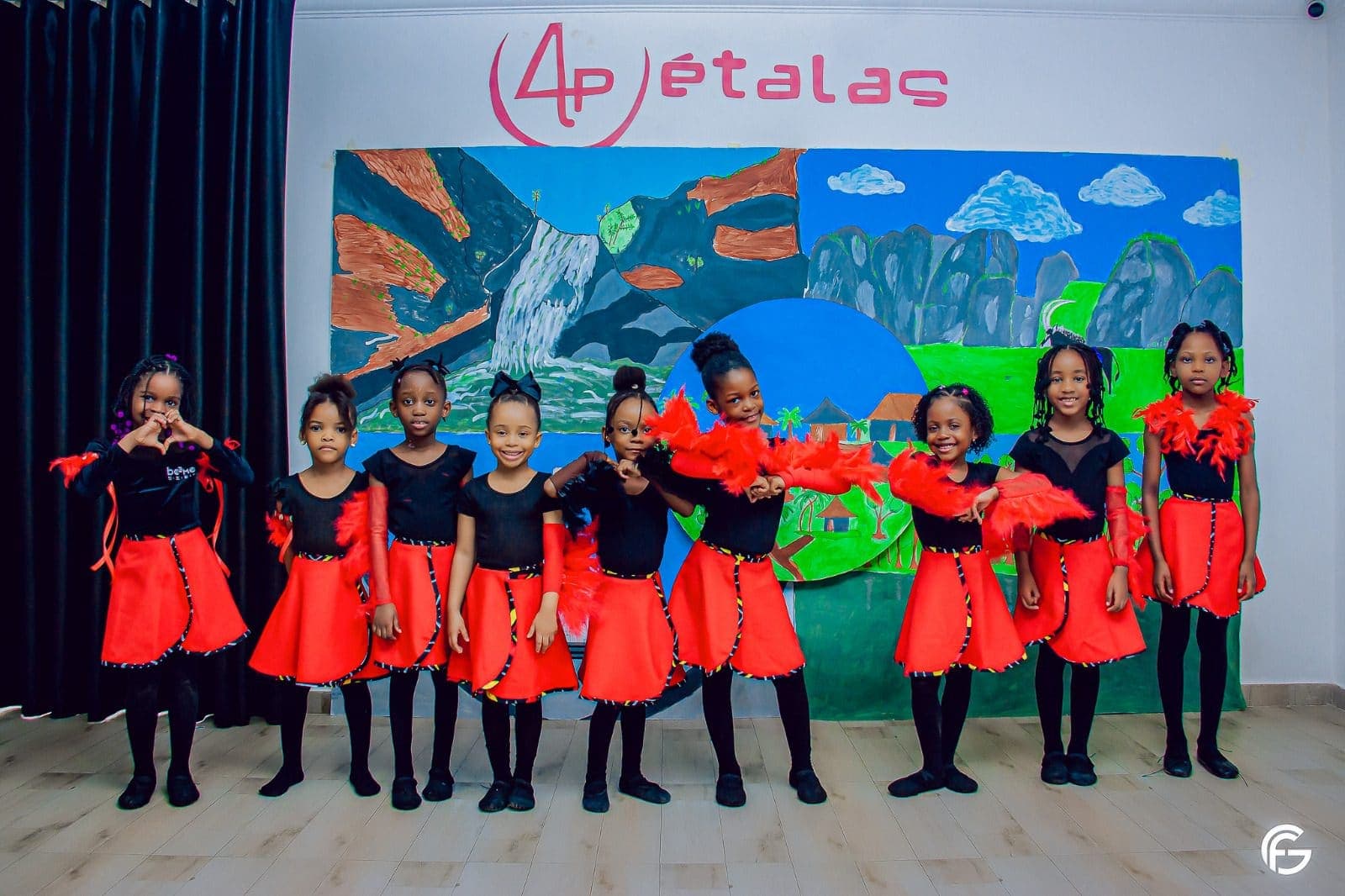 O grupo de dança, de vermelho e preto, em frente ao mural do 4 Pétalas